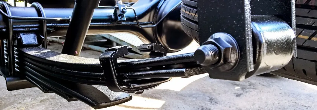 Close-up of a leaf spring pack and shackle under the rear of a vehicle