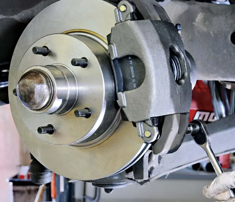 Brake disc and caliper on a wheel hub, with a spanner on one of the caliper bolts