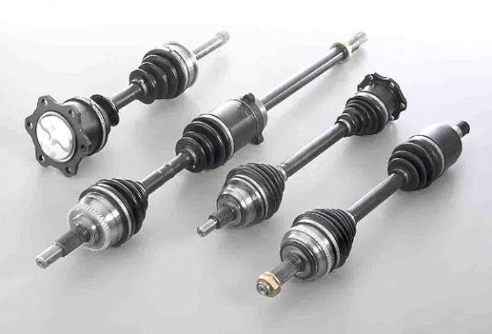 Four driveshafts with CV joints and rubber boots on a white background